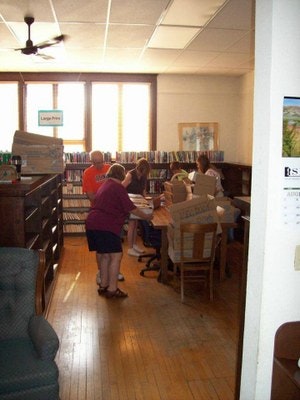 People inside a cozy library with bookshelves and a reading table.