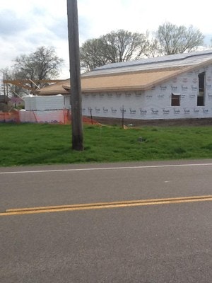 A construction site with a partially built house, a street in front, and safety fencing.
