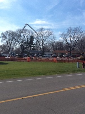 Construction site with a concrete pump, safety barriers, and equipment.