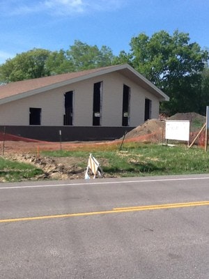 A house under construction with a road in the foreground and a clear sky above.