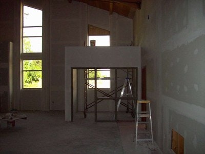 An unfinished room under construction with drywall, a ladder, and scaffolding.