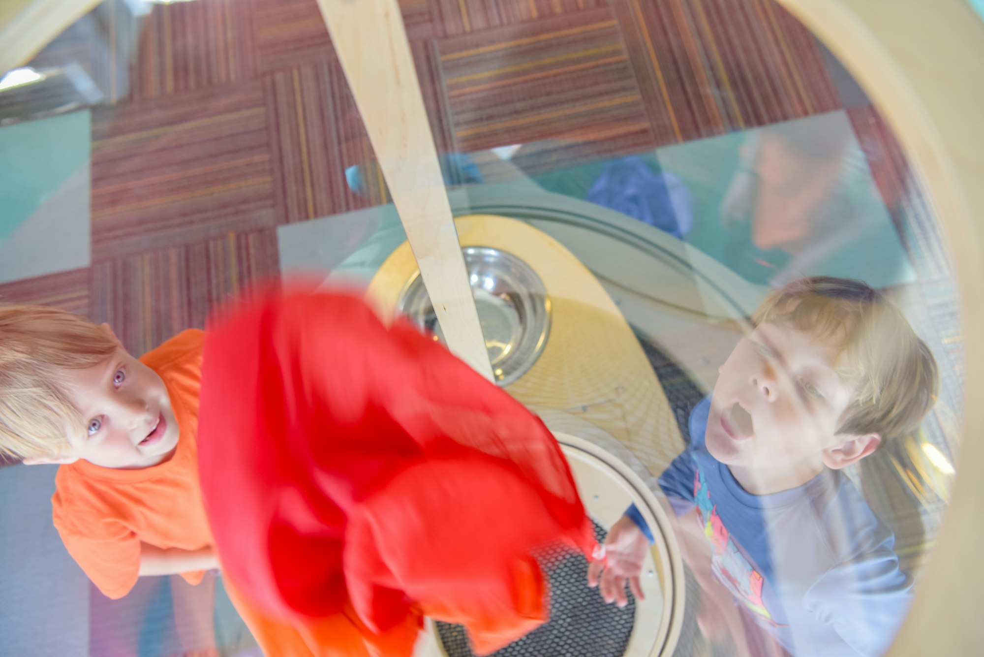 Children looking through a circular window, creating a distorted and playful perspective.