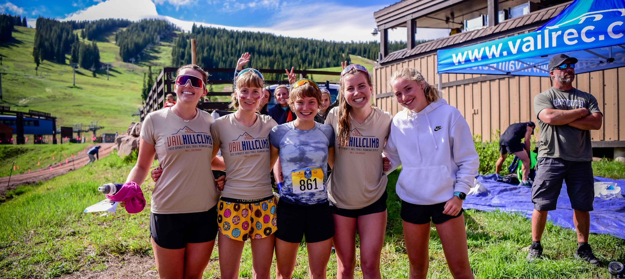 Group of happy participants at Vail Hill Climb event, with a mountainous background on a sunny day.