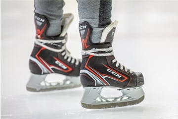 A pair of ice hockey skates on an ice rink.