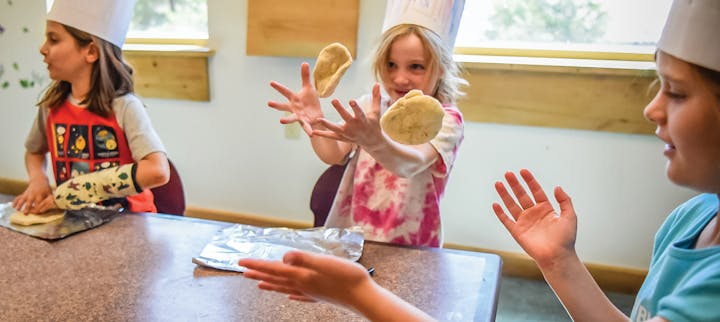 Children in chef hats tossing dough at Camp Vail
