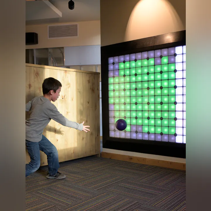 A child playing with a large interactive light wall game.