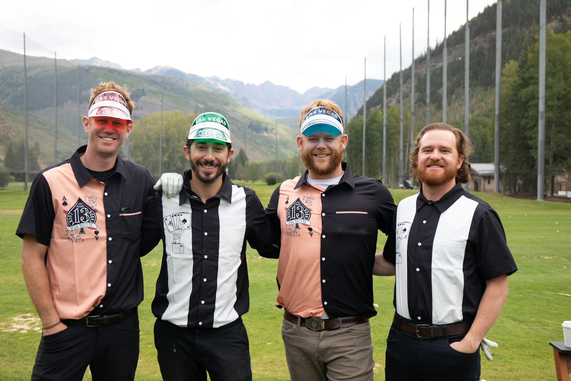 Four men posing on a golf course, dressed in themed outfits with playful hats.