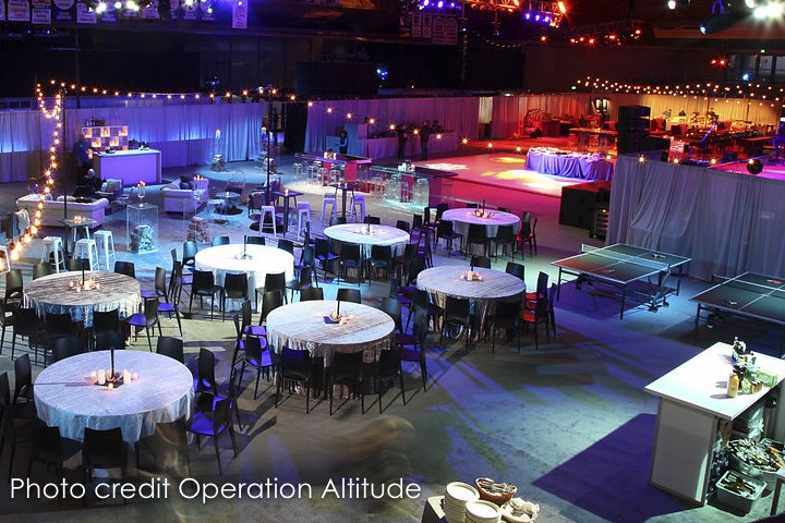 An event space with tables, mood lighting, and a stage set for a gathering or celebration.