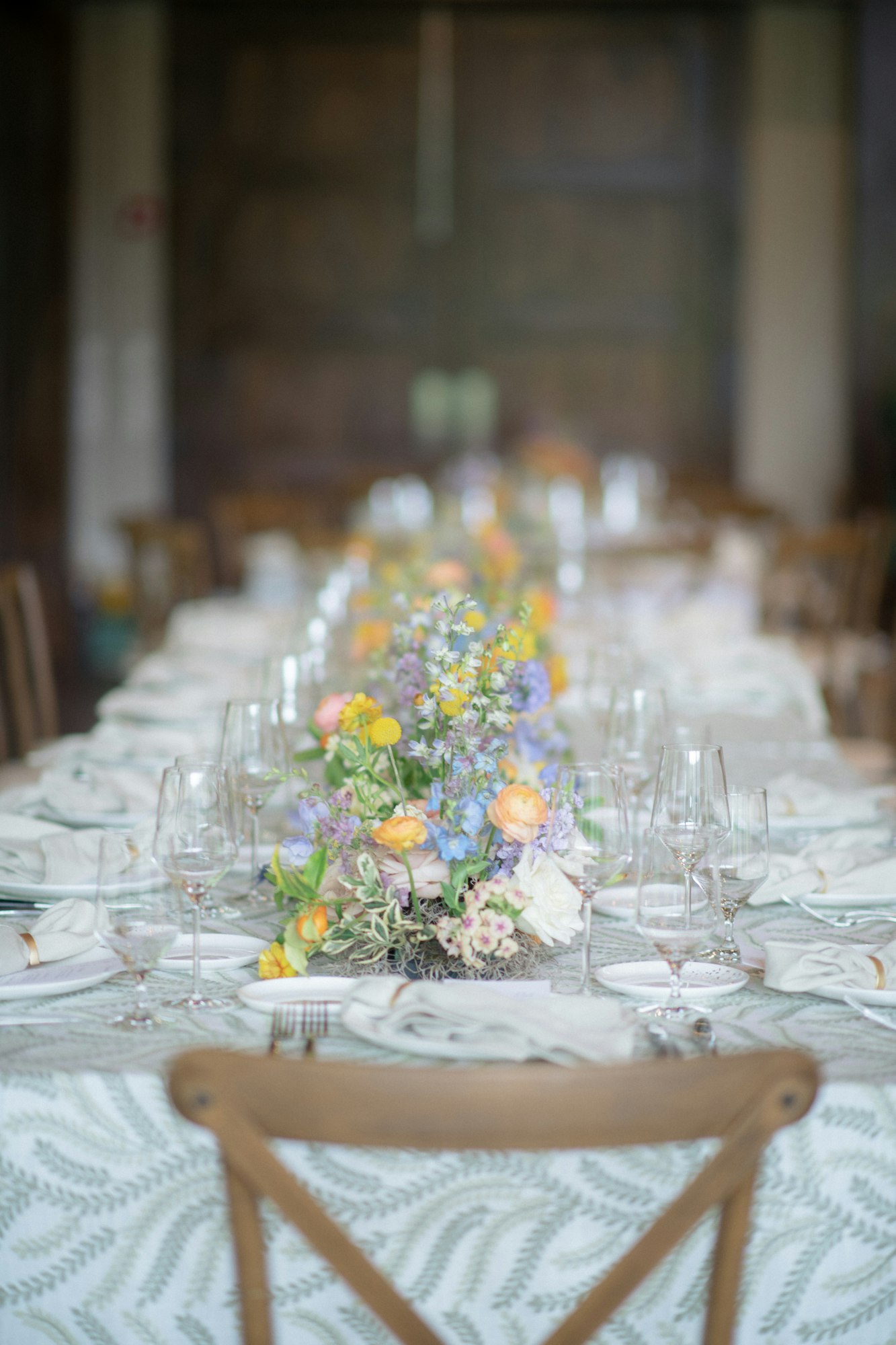 A beautifully set dining table with floral centerpieces, elegant glassware, and patterned tablecloth, creating a festive atmosphere.
