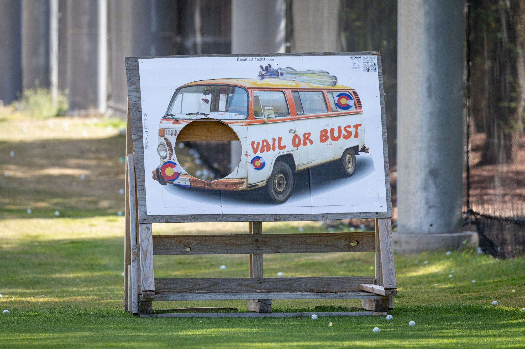 A golf target board with a retro van design reading "VAIL OR BUST" and Colorado flags, with a hole for golf balls to go through.