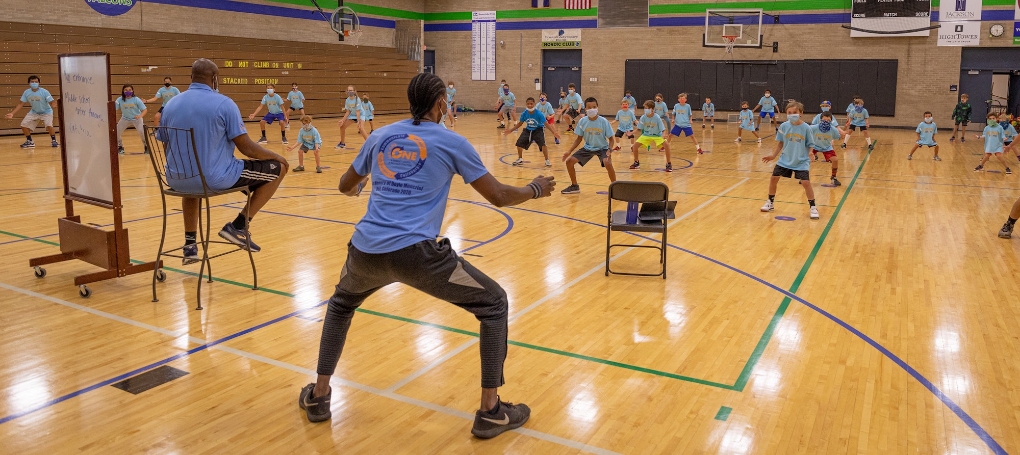 Group exercise class with instructor leading children in a gym.