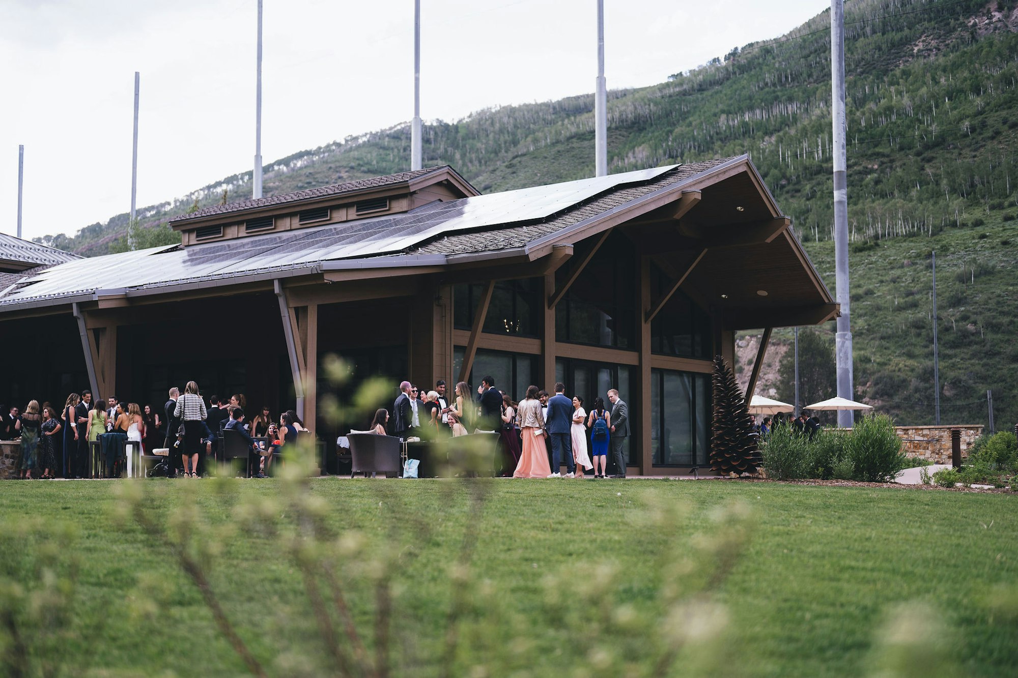Elegant gathering at a mountain lodge with people mingling outside.