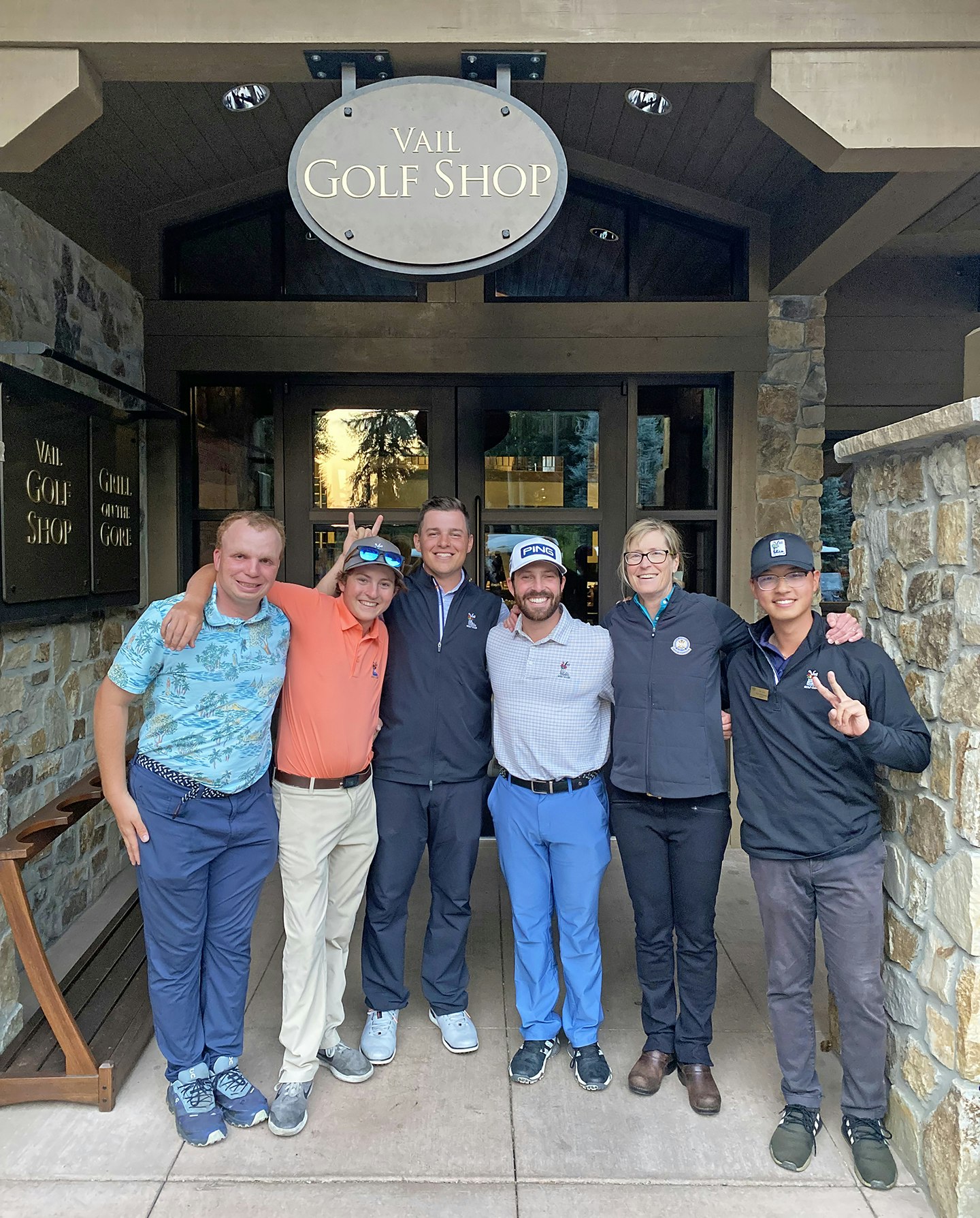Group of seven people smiling in front of the Vail Golf Shop.