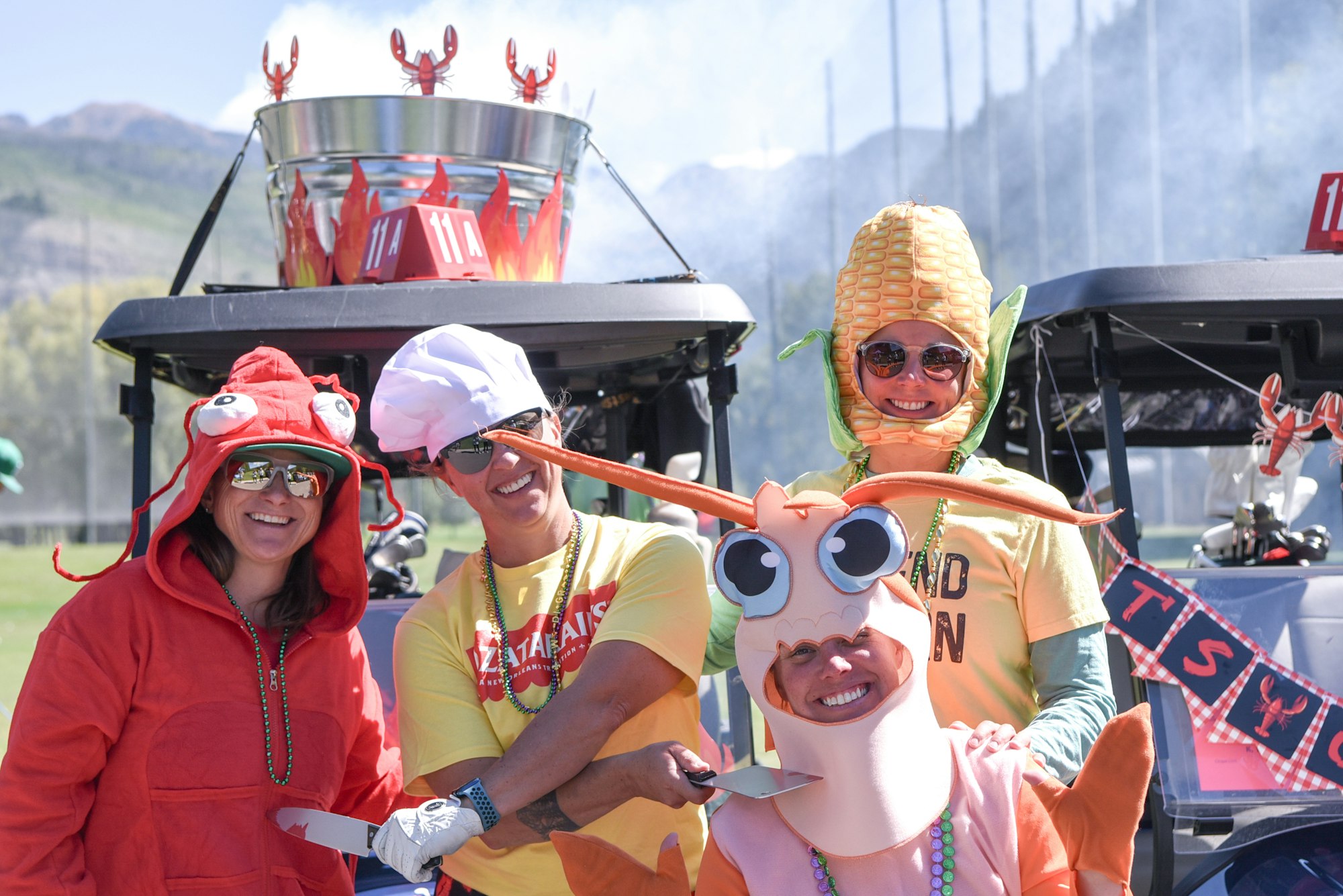 People in playful seafood and corn costumes posing by a decorated vehicle.