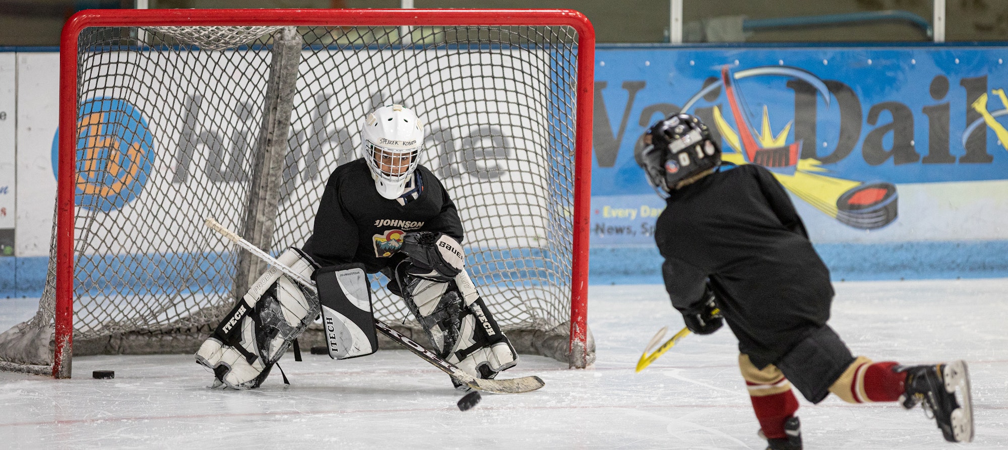 A hockey goalie is ready to block a shot from a player on ice.