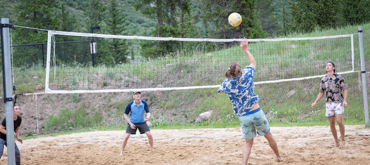 People playing beach volleyball outdoors.