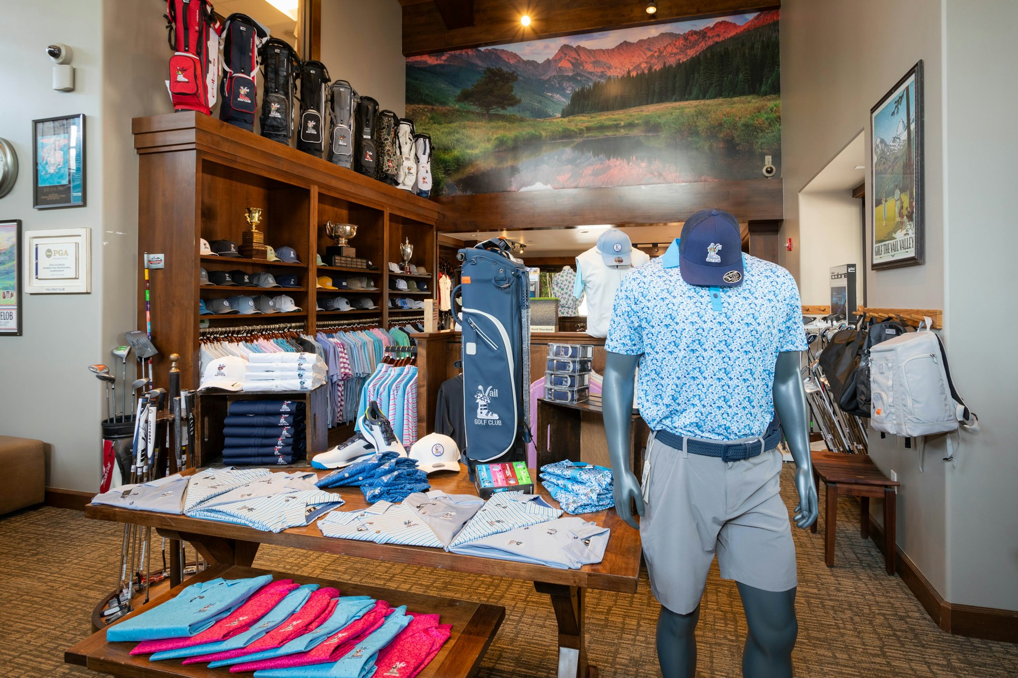 Golf shop interior with apparel, clubs, and accessories on display, featuring a mannequin dressed in golf attire.