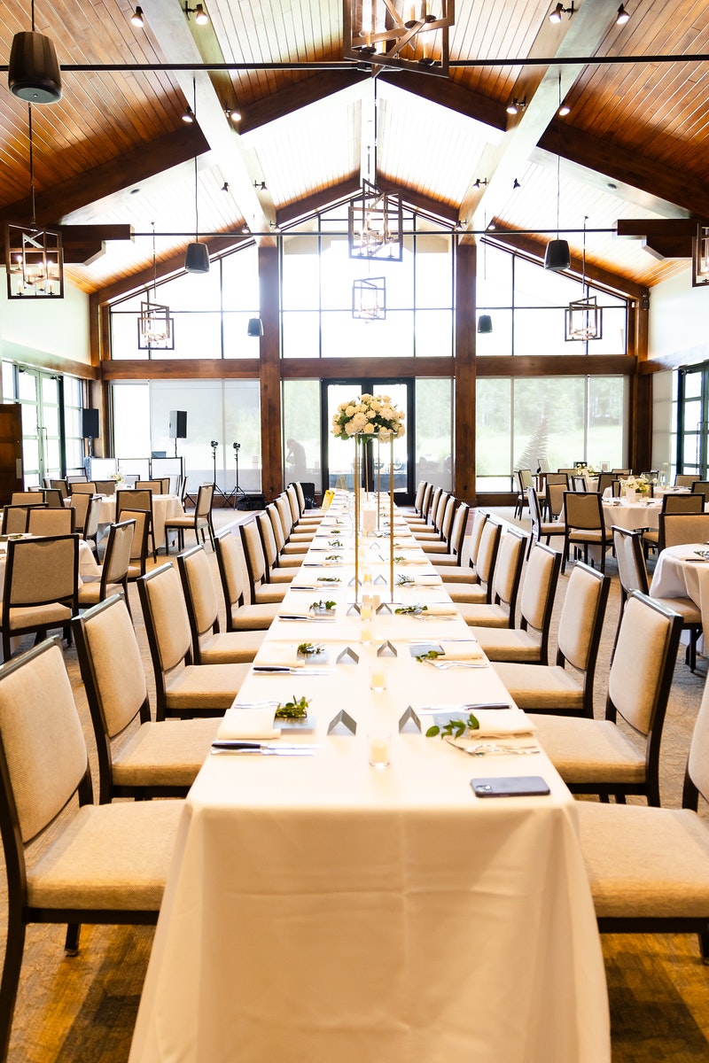 Elegant banquet hall with decorated tables, chairs, and modern lighting fixtures.