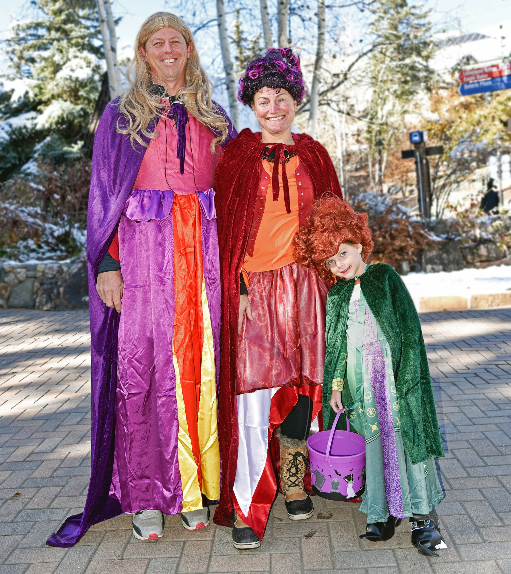 A group of three in colorful costumes, with snowy background, ready for a festive occasion.