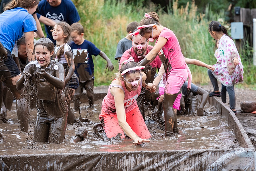 Children playing in a mud pit, laughing and enjoying a messy outdoor activity.
