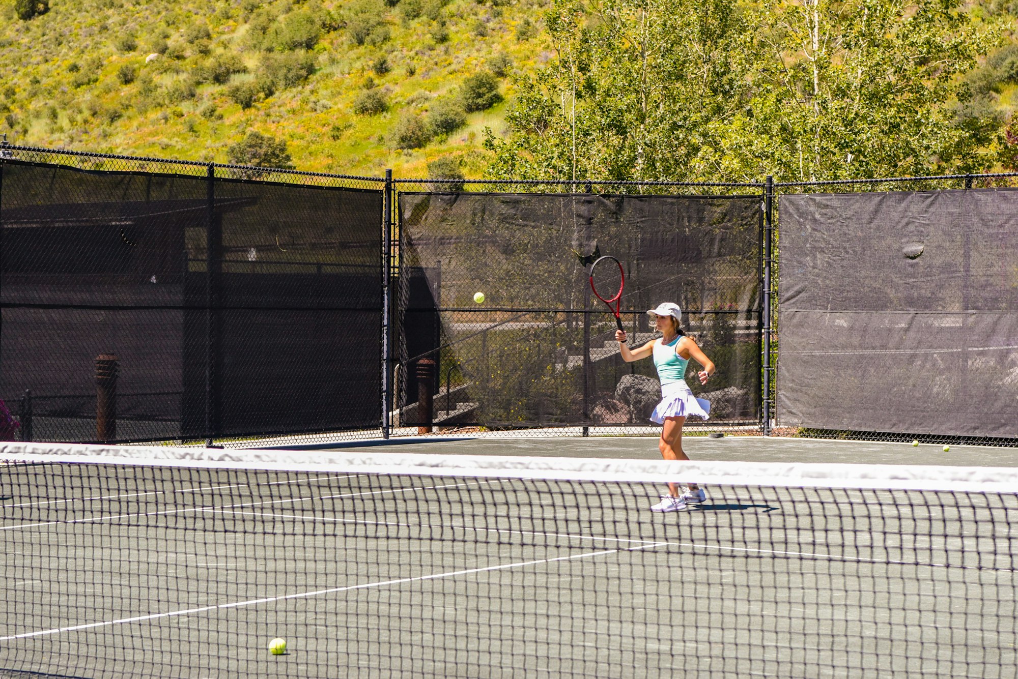 A tennis player on an outdoor court ready to hit a ball with a racket.