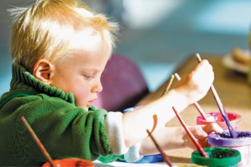 A child painting with bright colors, focused and enjoying art.