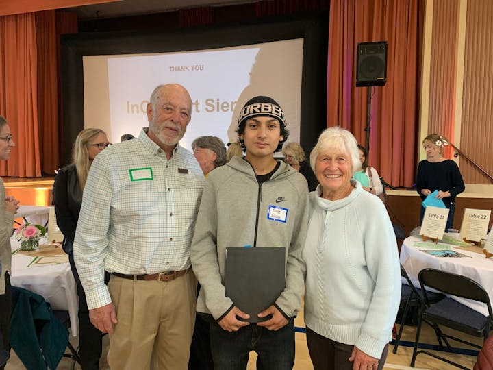 Three people posing for a photo at an event with a "THANK YOU" slide in the background.