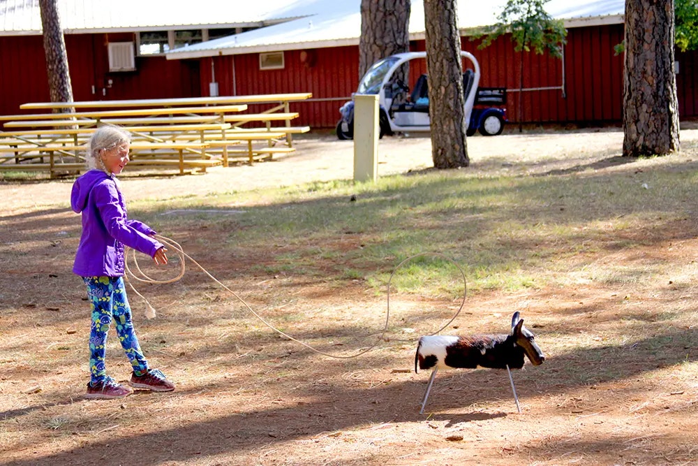 girl lassoing a toy cow