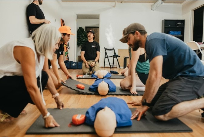 People practicing CPR on mannequins in a training session.