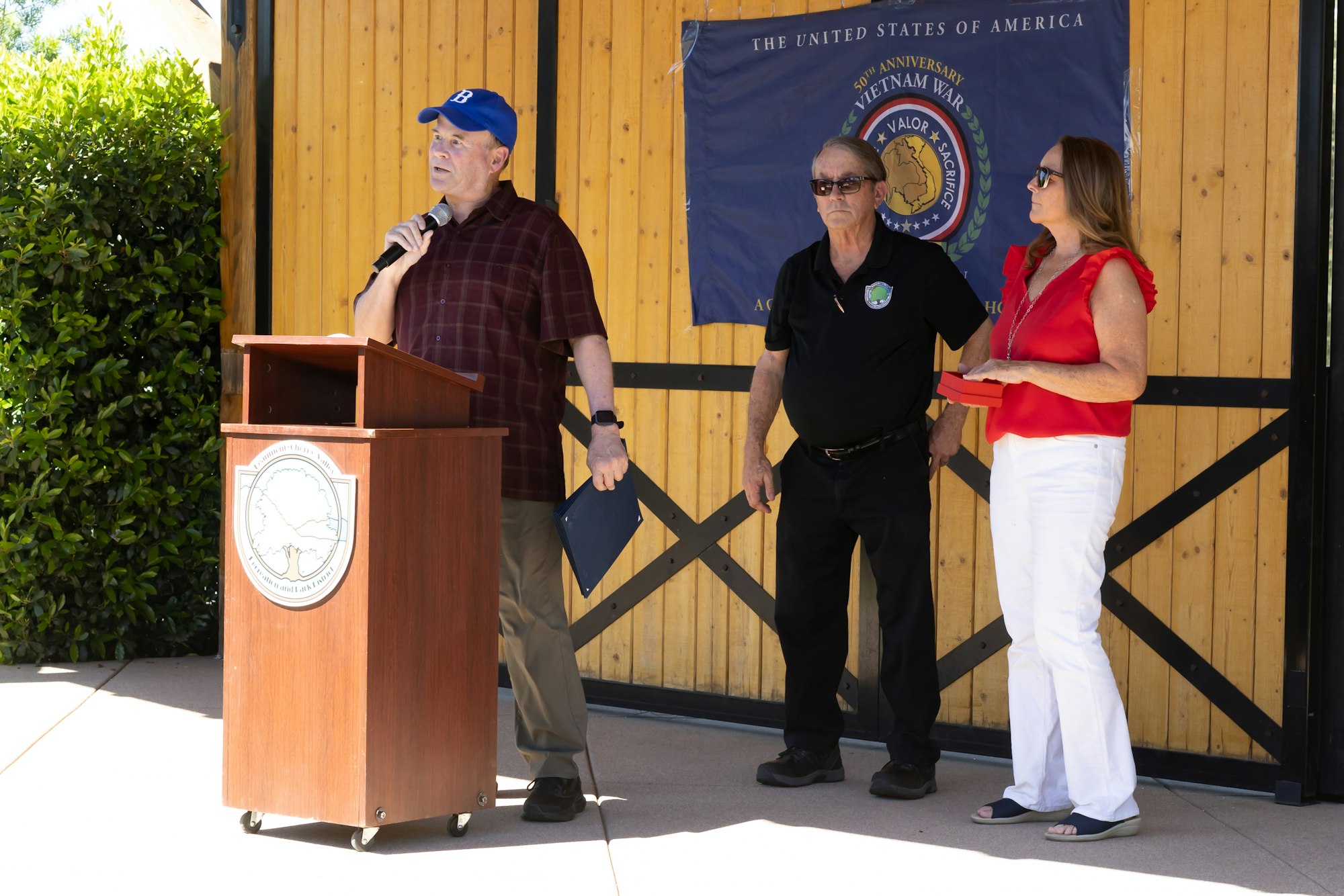 An event with speakers at a podium, discussing the 50th anniversary of the Vietnam War, featuring three individuals.
