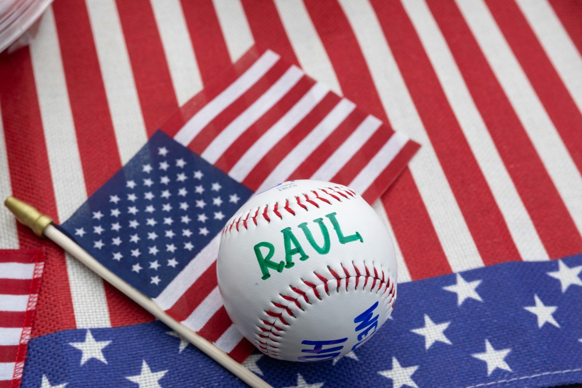 A baseball with "RAUL" written on it, placed on American flags.