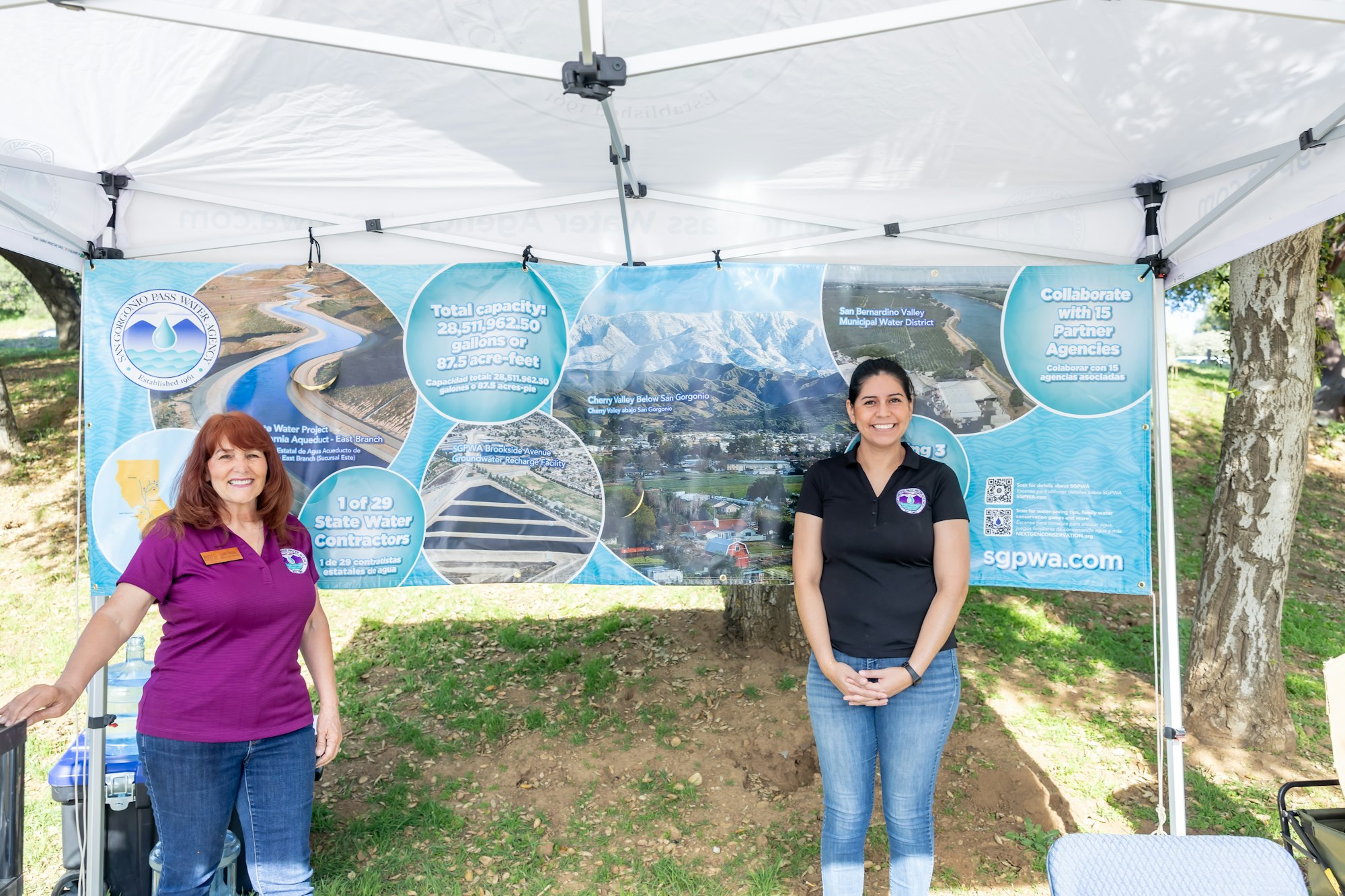 Two people at a water agency booth with a large informational banner about water capacity and state contractors.