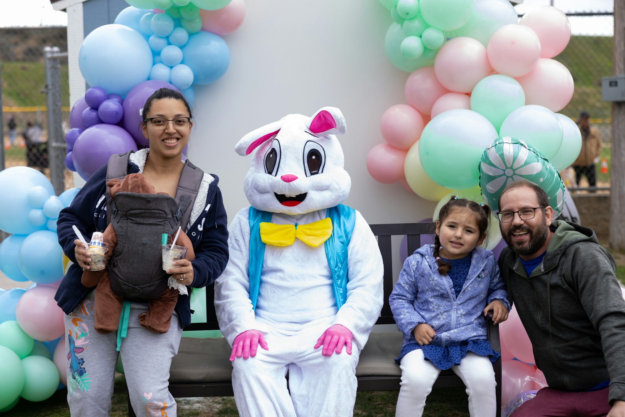 A group of people, including a person in a bunny costume, posing with colorful balloons.