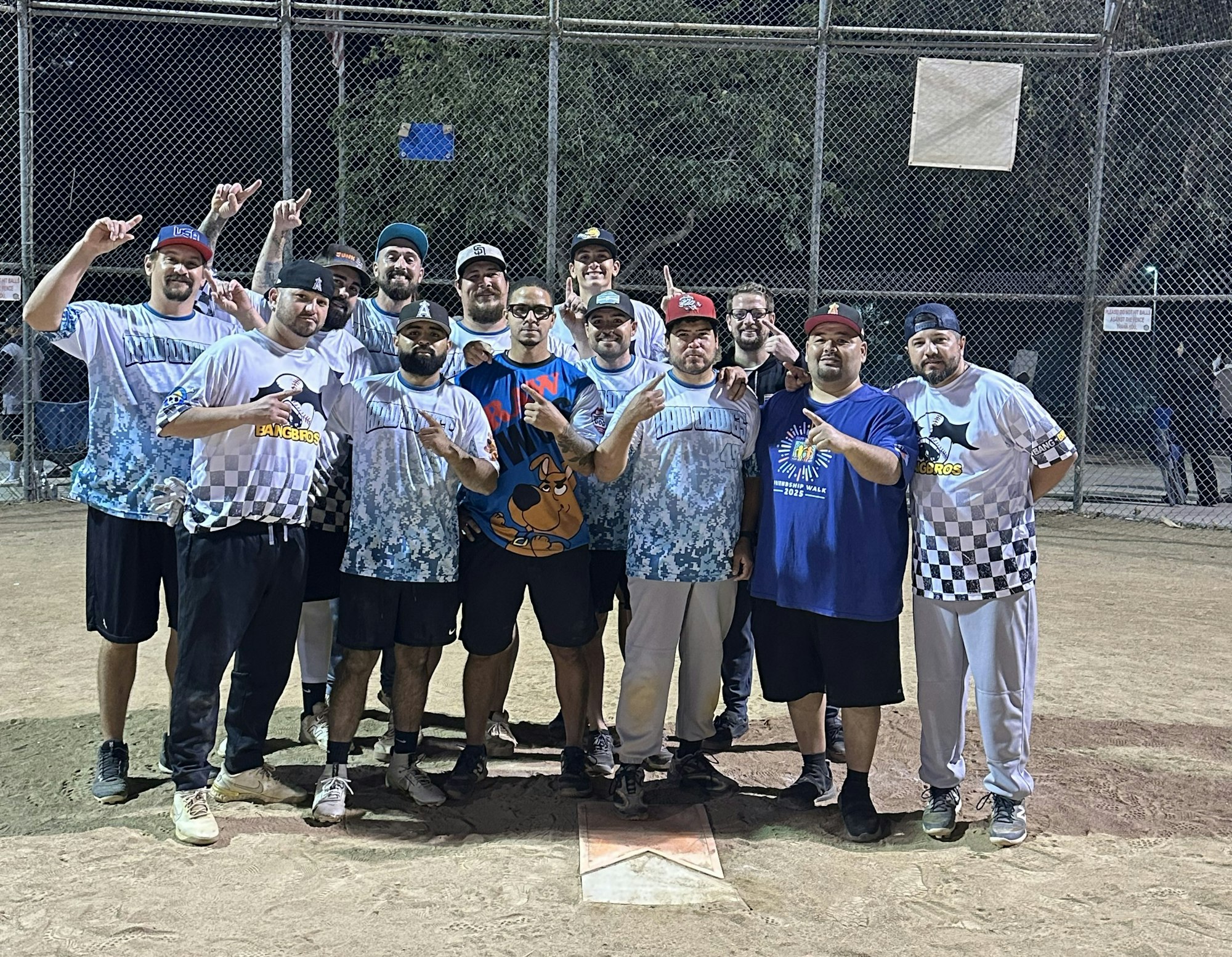 A group of men in matching sports jerseys posing on a baseball field.