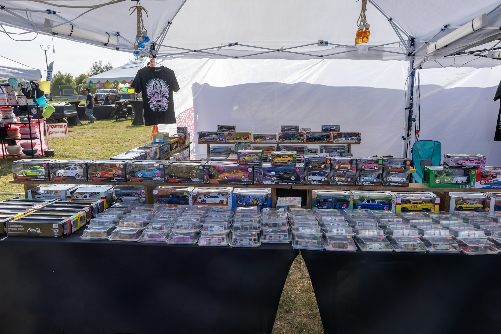 A market stall displaying various model cars in packaging under a tent.