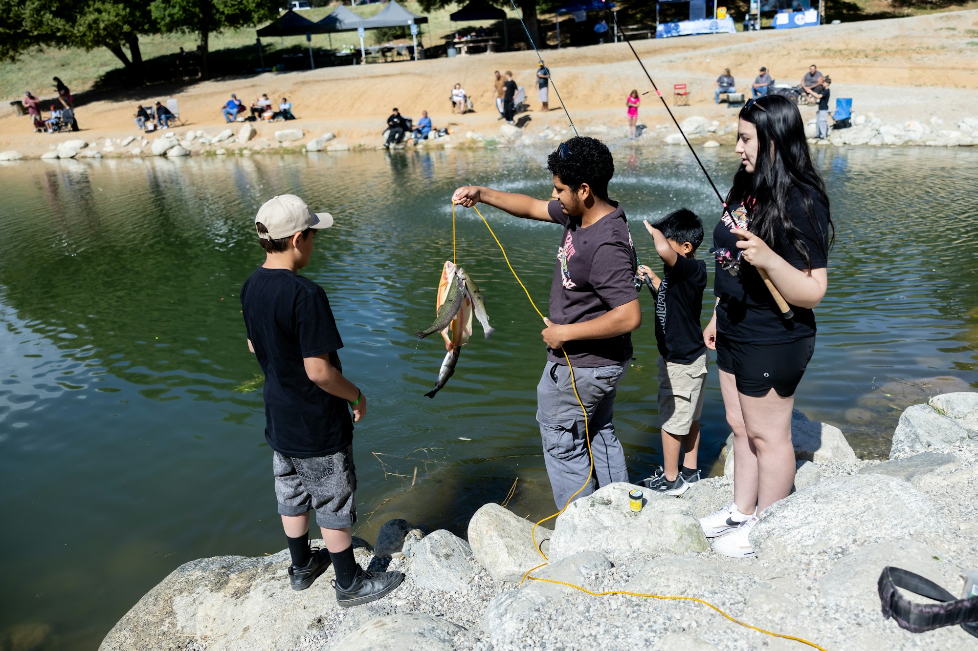 A group of people fishing by a pond, showcasing their catch.