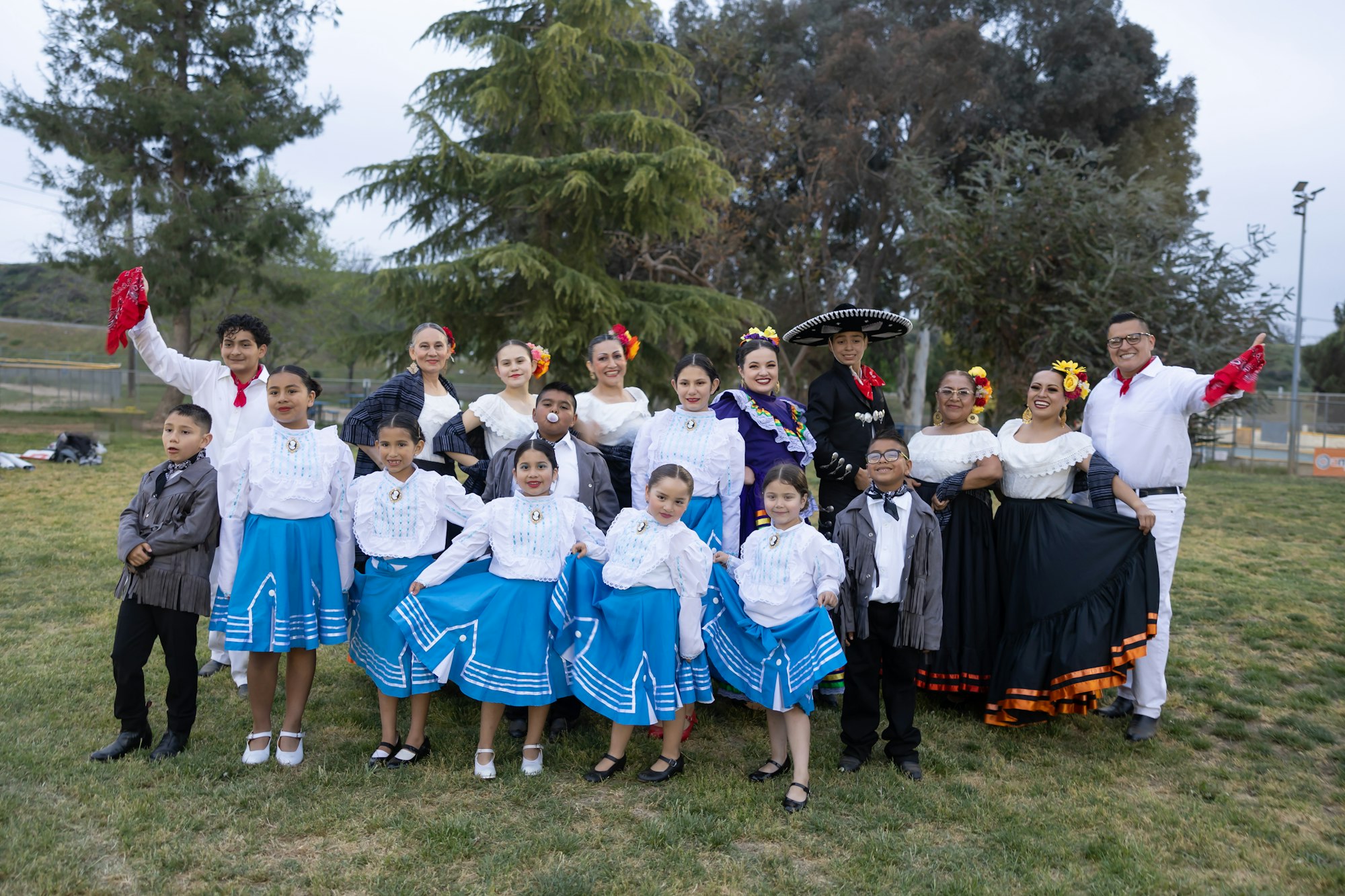A group of people, including children, in traditional festive clothing posing outdoors.