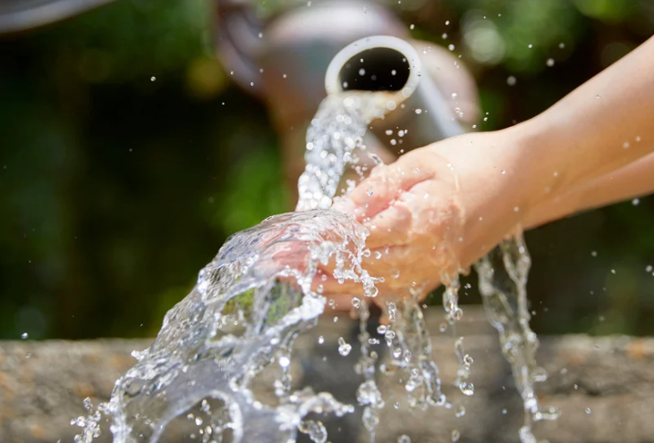 A hand catching water flowing from a spout, capturing the beauty of nature and the refreshing essence of water.