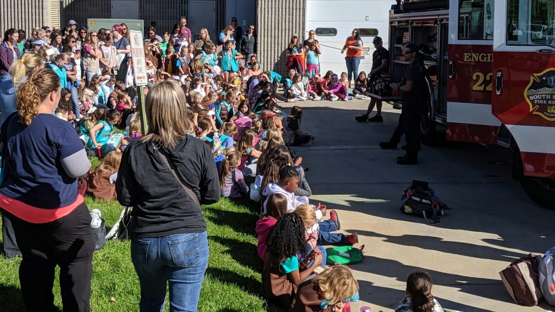 A group of people gathered near a fire truck for a demonstration or event.
