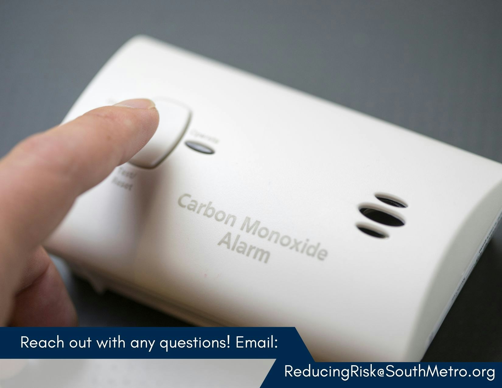 Finger pressing button on a carbon monoxide alarm. Contact info for questions: ReducingRisk@SouthMetro.org.