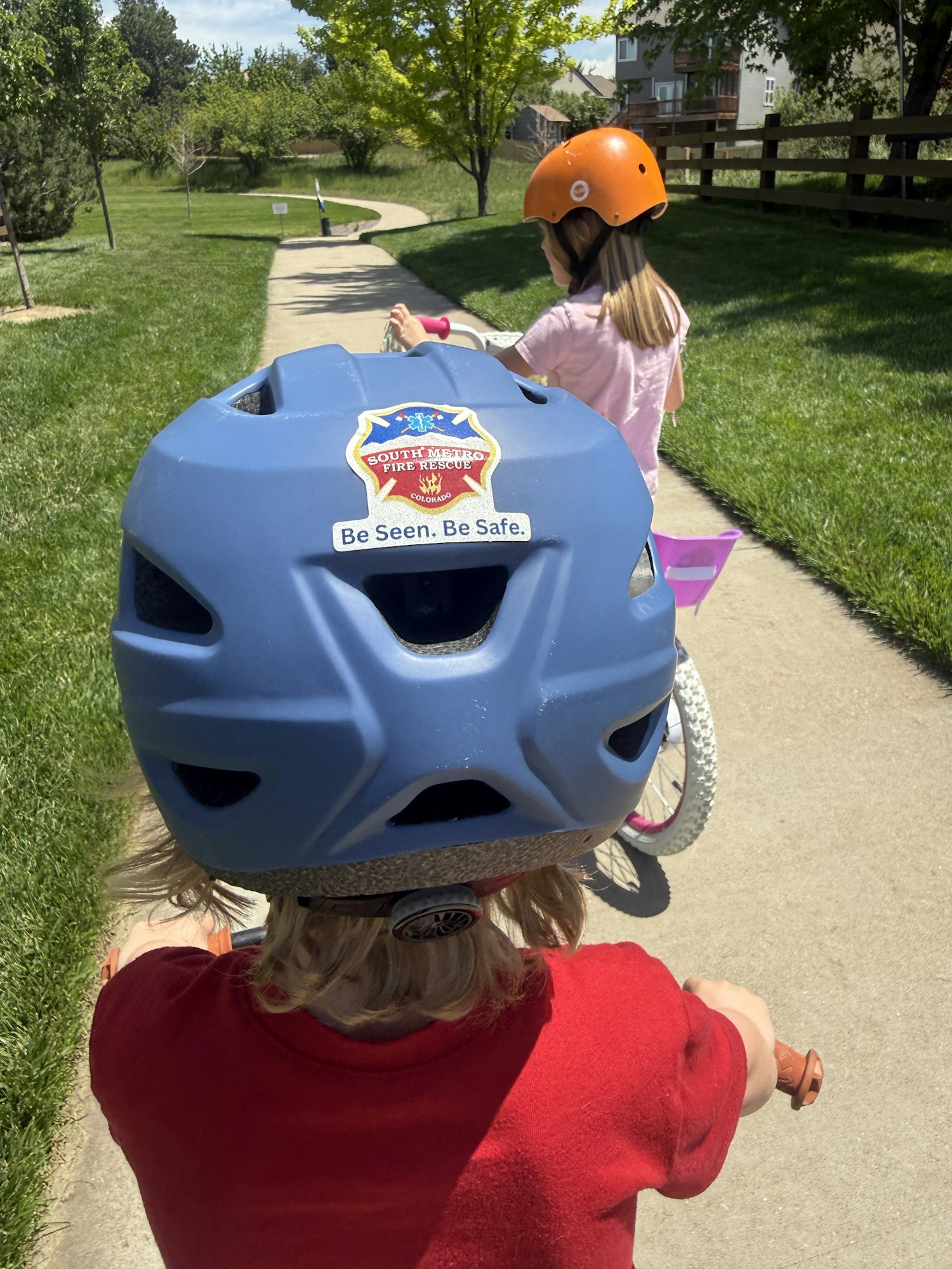 Two kids riding bikes on a pathway, wearing helmets, enjoying a sunny day outdoors. Safety first!