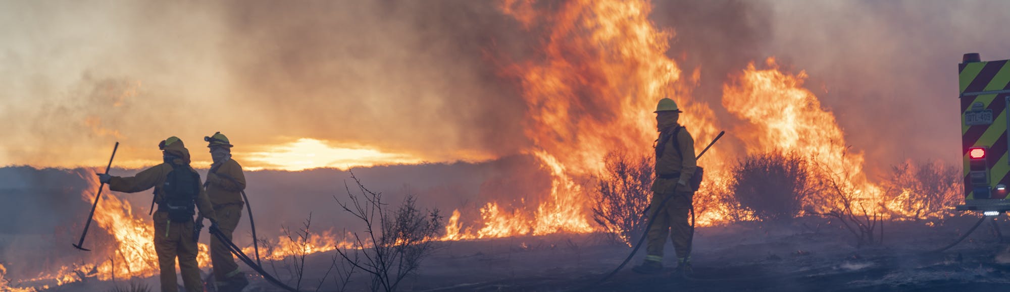 Firefighters battle a raging wildfire. Smoke and flames dominate as they work tirelessly to control the inferno.