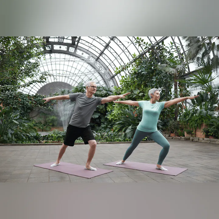 Two people practicing yoga in a greenhouse.