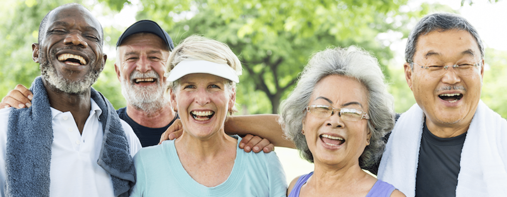 A group of happy, diverse senior adults are laughing together outdoors.