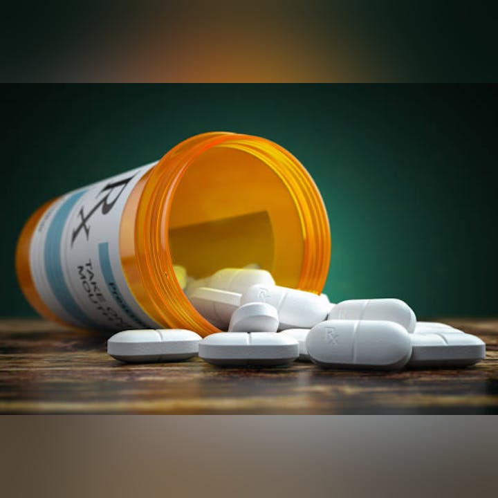 Spilled pill bottle with white tablets on a wooden surface.