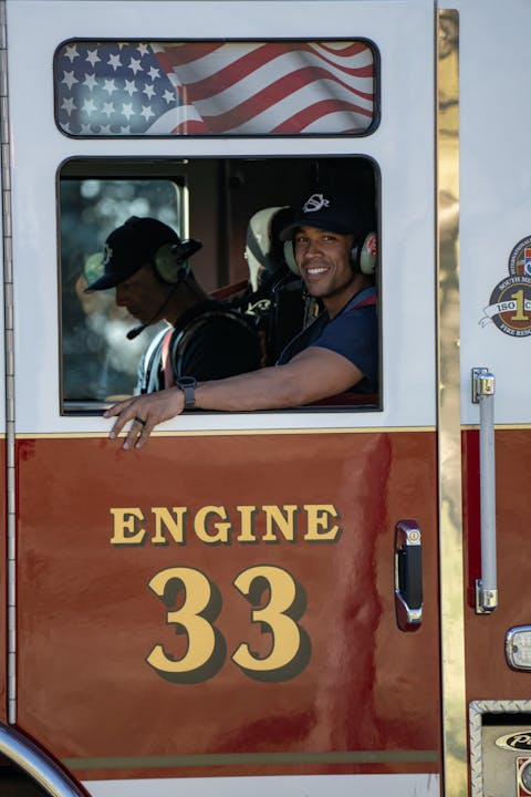 Firefighter smiling from fire engine.