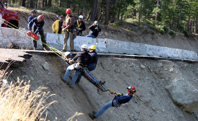 Rescue workers training with a stretcher on a slope.