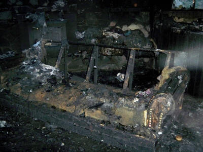 Burned interior with charred furniture and debris.