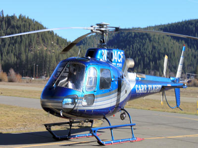 A blue and white helicopter on the ground with its rotors spinning.