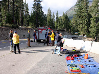 Emergency personnel with equipment on a road near a forest, possibly preparing for a rescue operation.